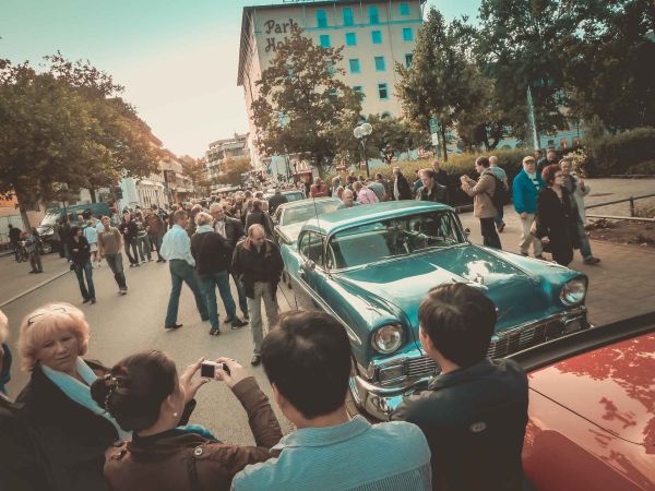 Menschen stehen um die US-Oldtimer die an der Fürther Freiheit neben dem New Orleans Festival in Reihe aufgestellt sind.