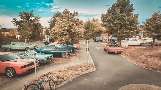 Mehrere klassische und neue US-Cars stehen auf einem Parkplatz